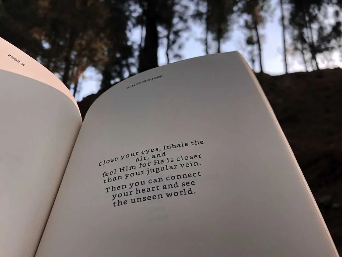 In Love with God lying open beneath tall pines, hillside light behind the pages.