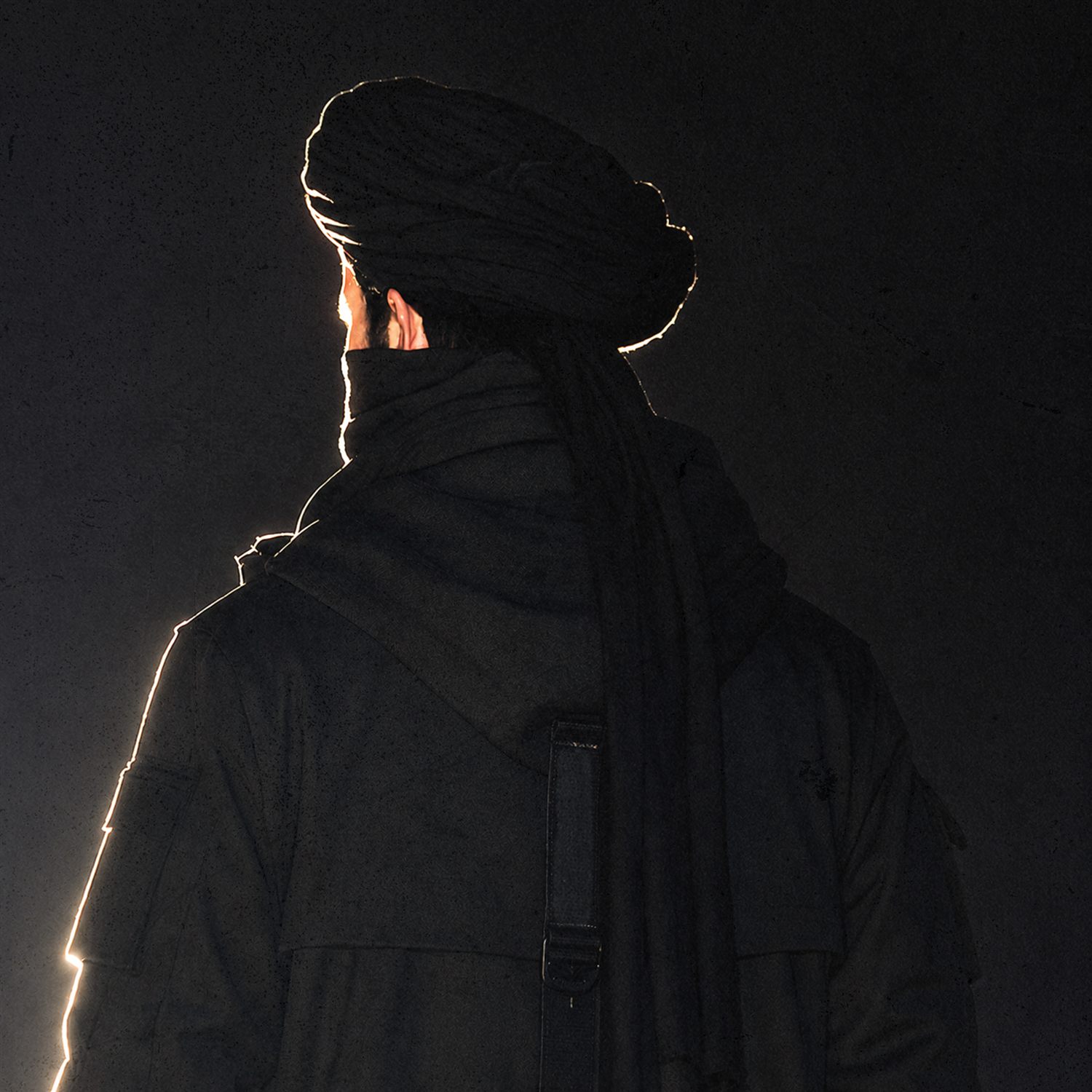 REBEL X, seen from behind, rim-lit against the dark.